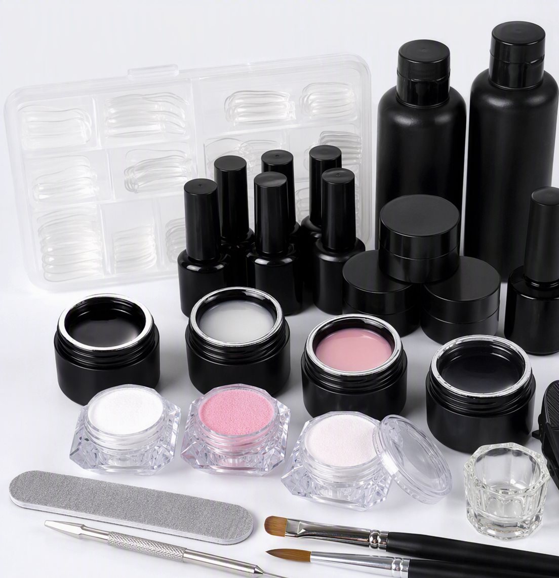 Complete nail extension kit: gel polish bottles, acrylic powder jars, nail tips and tools on white background